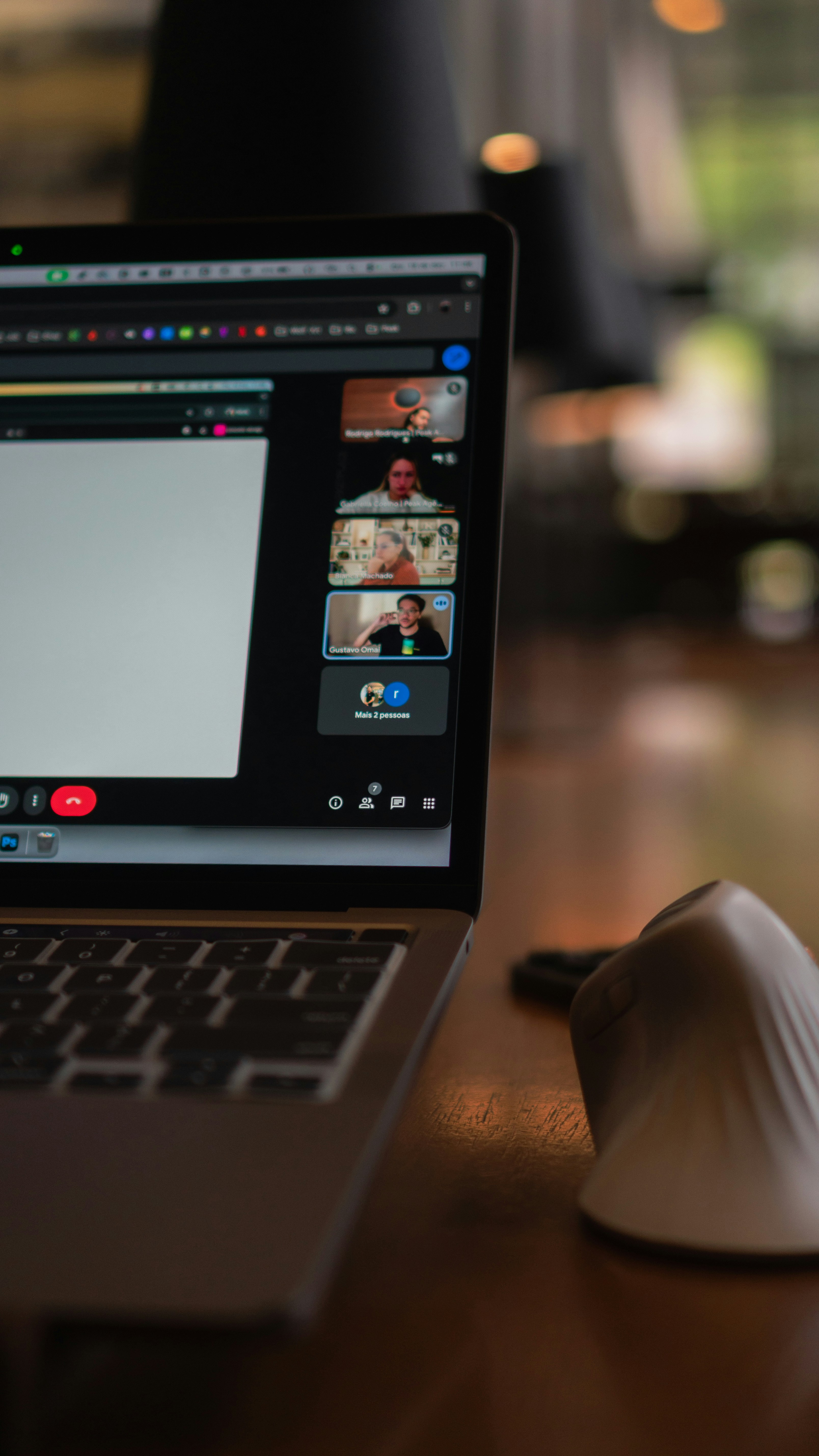 A laptop on a warm wooden table showing a live video call with the team.